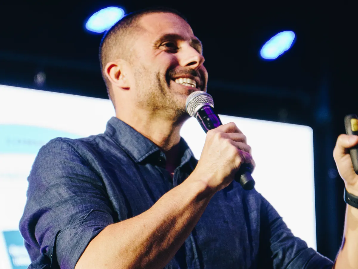 Charles G. Martins sorrindo ao microfone durante palestra